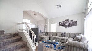 A living room with a staircase, a sectional sofa, a coffee table, and a rug. - Calle Azul in Las Vegas (North Las Vegas)