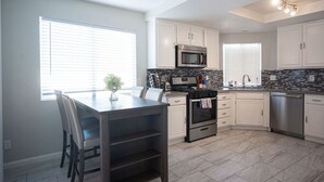 A modern kitchen with white cabinets, a stainless steel microwave, a stove, and a dishwasher. - Calle Azul in Las Vegas (North Las Vegas)