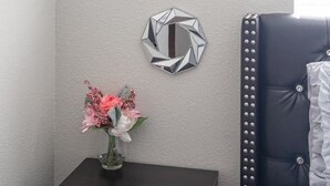 A room with a grey wall, a small table with a vase of flowers, and three geometric wall decorations. - Calle Azul in Las Vegas (North Las Vegas)