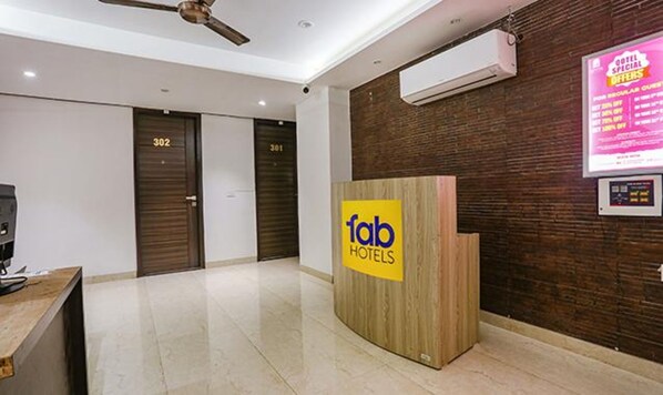 Zona de recepción de hotel con un mostrador de madera, puertas cerradas con las etiquetas 302 y 301, y un equipo de aire acondicionado en la pared.