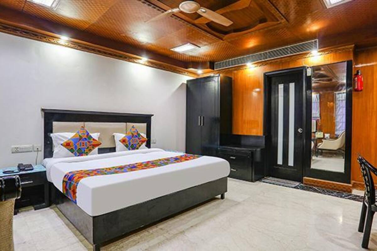 A modern hotel room with a large bed, a wardrobe, a desk, and a chair.