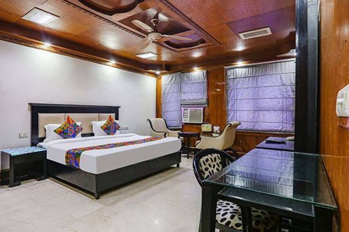 A hotel room with a large bed, a desk, and a chair.