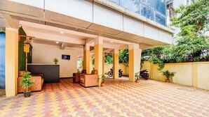 Un vestíbulo de hotel con mostrador de recepción, zona de estar y plantas en macetas.