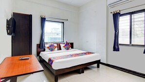 Habitación de hotel con cama, una mesa de madera, televisor y ventana con cortinas.