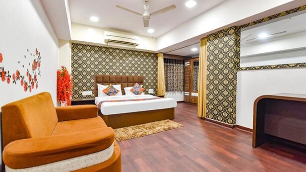 A modern hotel room with a bed, a sofa, a desk, and patterned walls. - Fabhotel Blue Moon I (Ahmedabad)