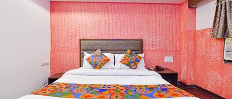 Quarto de hotel com cama grande, cabeceira, mesa de cabeceira e janela com cortinas.