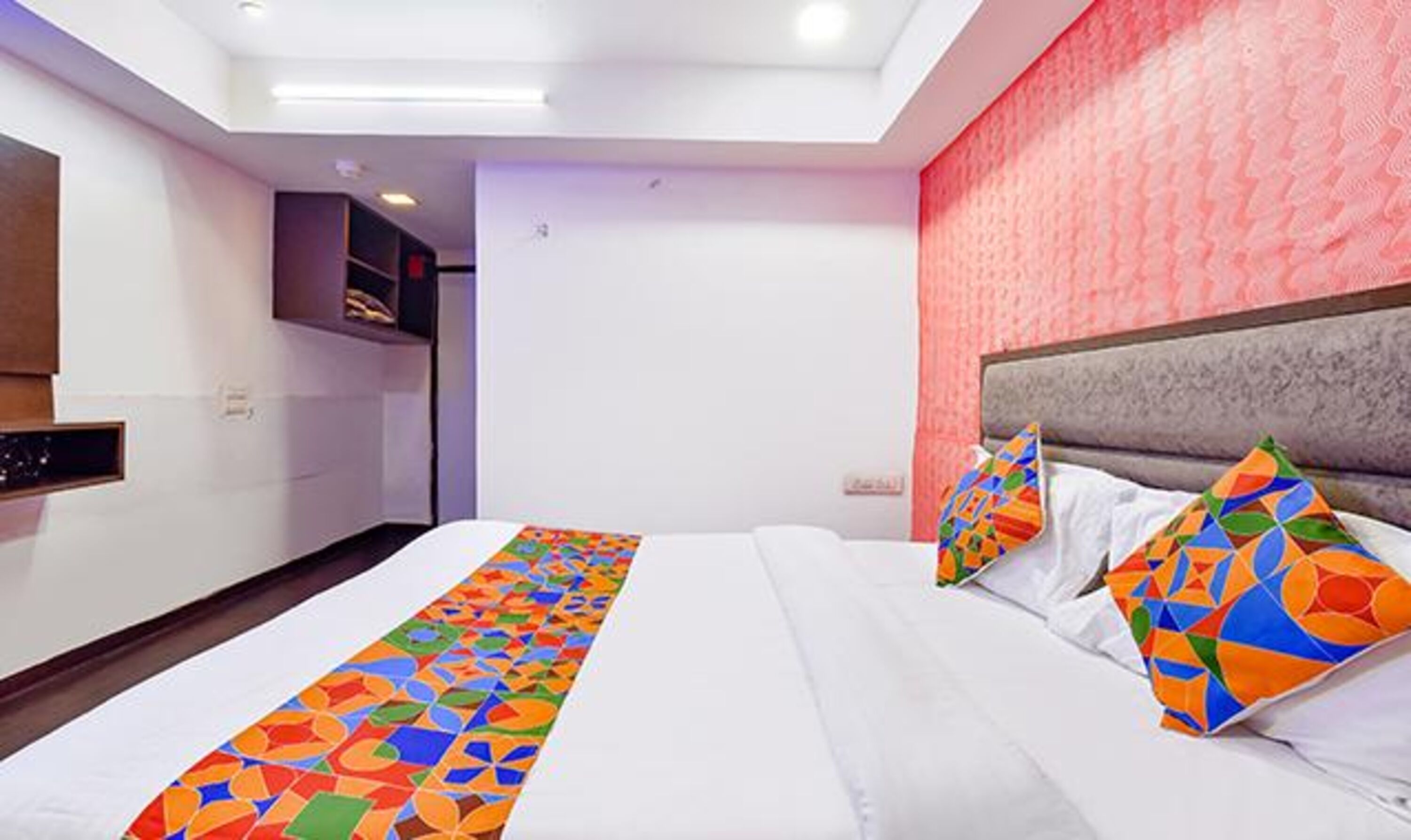 A hotel room with a large bed, a headboard, and a colorful runner.