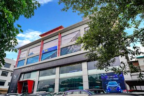 A modern building with a large glass facade, a prominent 'Mahindra' sign, and a 'Fab Hotels' sign above the entrance. - Fabhotel Lotus I (Surat)