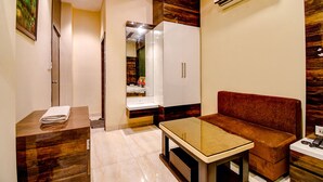 A modern living room with a sofa, a small table, and a cabinet. There is a mirror and an air conditioning unit on the wall. - Fabhotel Abis Inn (Kolkata)
