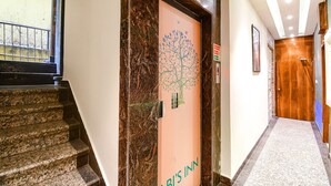 A hotel entrance with a marble staircase, a door with a tree design, and a sign indicating no smoking. - Fabhotel Abis Inn (Kolkata)