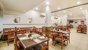 Tilava ravintola, jossa on puupöydät ja -tuolit, valkoiset seinät ja kattovalaisimet.