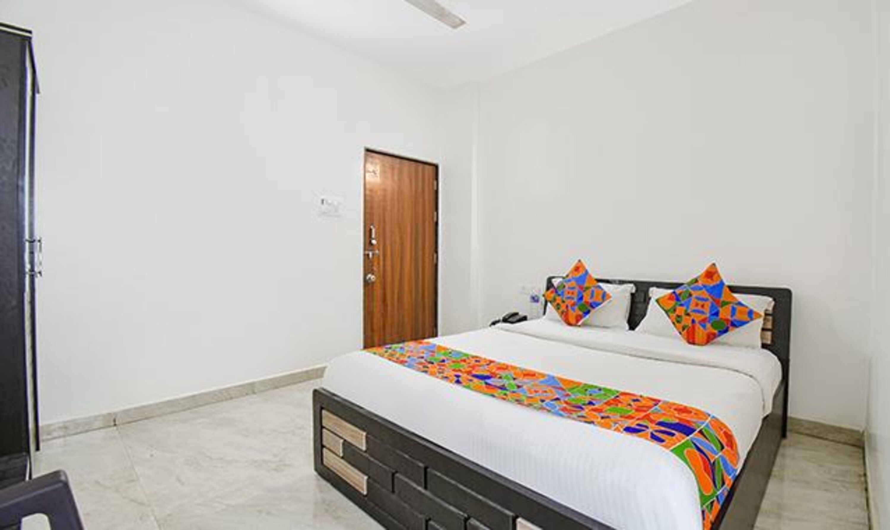 A bedroom with a bed, a wooden door, and a white wall.