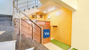 Un espace d’accueil comprenant un escalier, un comptoir de réception et une horloge murale.