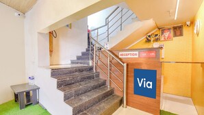 Un espace d’accueil avec un panneau indiquant « Via », un escalier et un panneau indiquant les modalités d’arrivée et de départ.