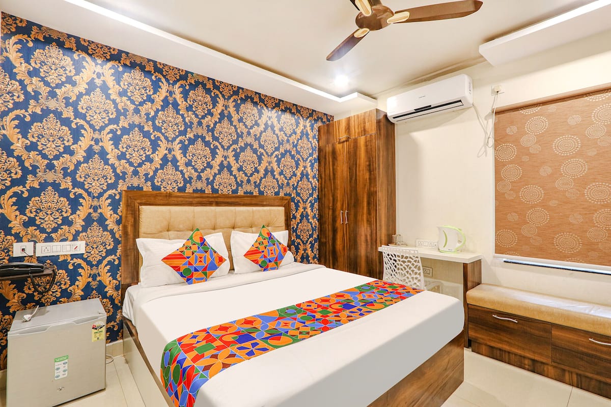 Ein Hotelzimmer mit Bett, Deckenventilator, Klimaanlage, Nachttisch und Kleiderschrank.