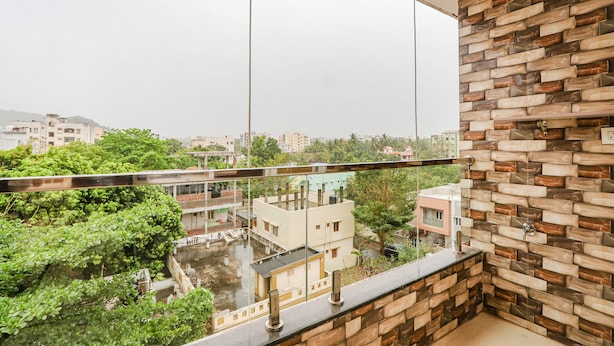 A balcony with a view of a residential area, a stone wall, and a metal railing.