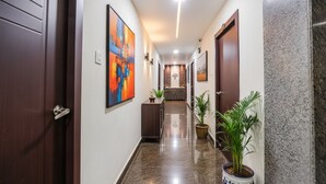 A hallway with wooden doors, a marble floor, and potted plants.