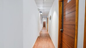 A long, narrow hallway with wooden flooring and white walls.