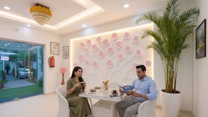 A modern interior with a glass door leading outside, a wall with a floral design, and a large potted plant. - FabHotel Frolic Luxury Stay (Noida)