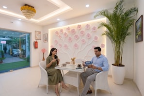 A modern interior with a glass door leading outside, a wall with a floral design, and a large potted plant. - FabHotel Frolic Luxury Stay (Noida)
