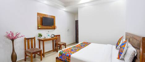 Un dormitorio con cama, escritorio, silla, televisor y ventilador de techo.