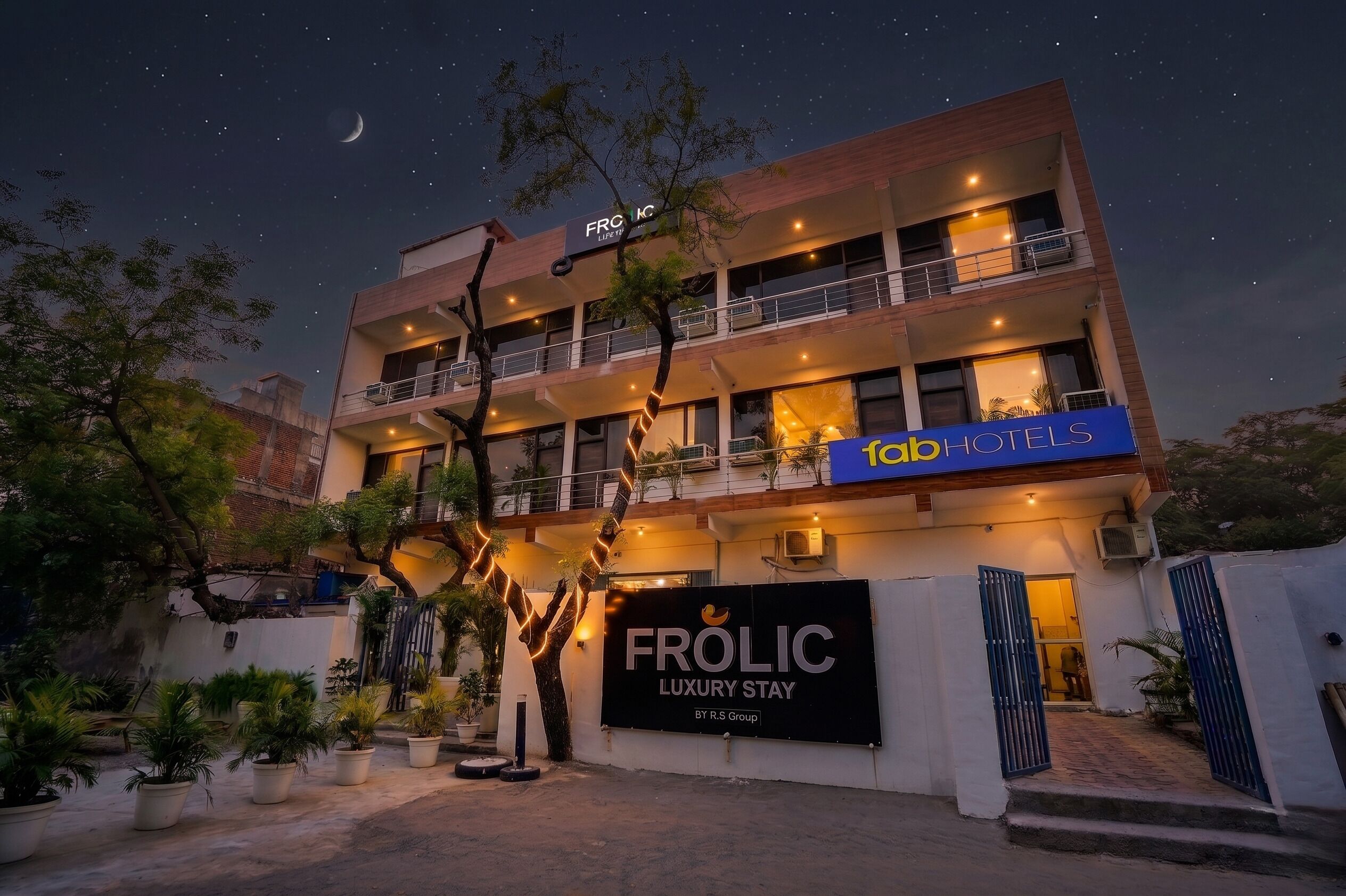 Un edificio a più piani con balconi, un cartello con su scritto 'FROLIC LUXURY STAY BY R.S Group' e un cartello 'TOB HOTELS'.