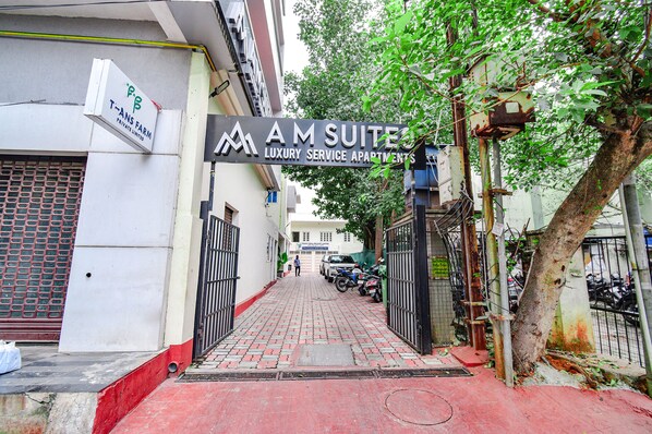 A gated entrance to a building with a sign for 'AM SUITES LUXURY SERVICE APARTMENTS'.