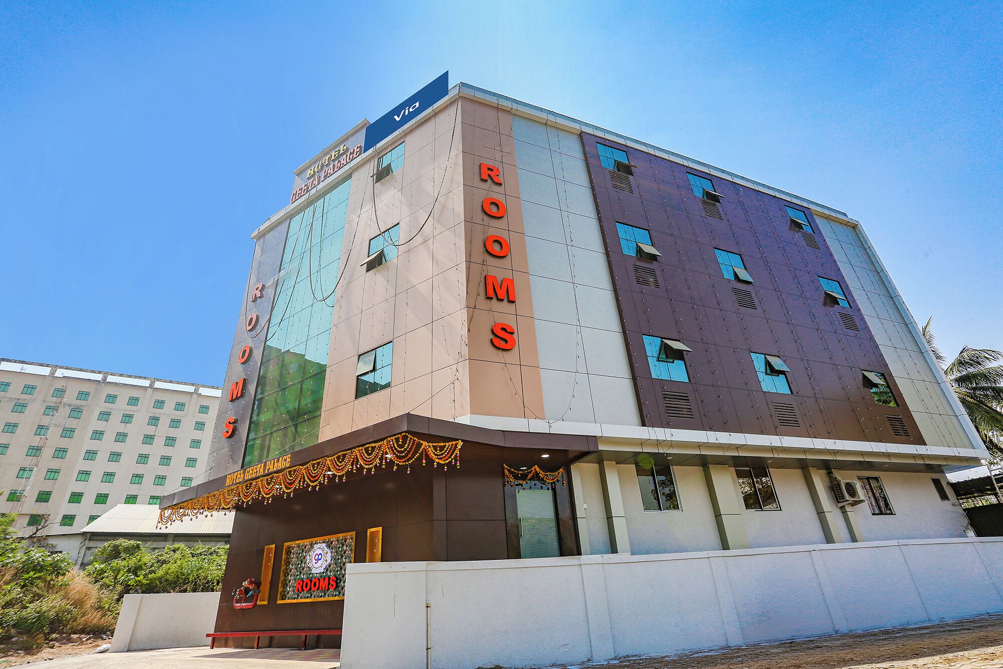 A multi-story hotel with a modern design, featuring a prominent 'HOTEL' sign and 'ROOMS' signage on the facade.
