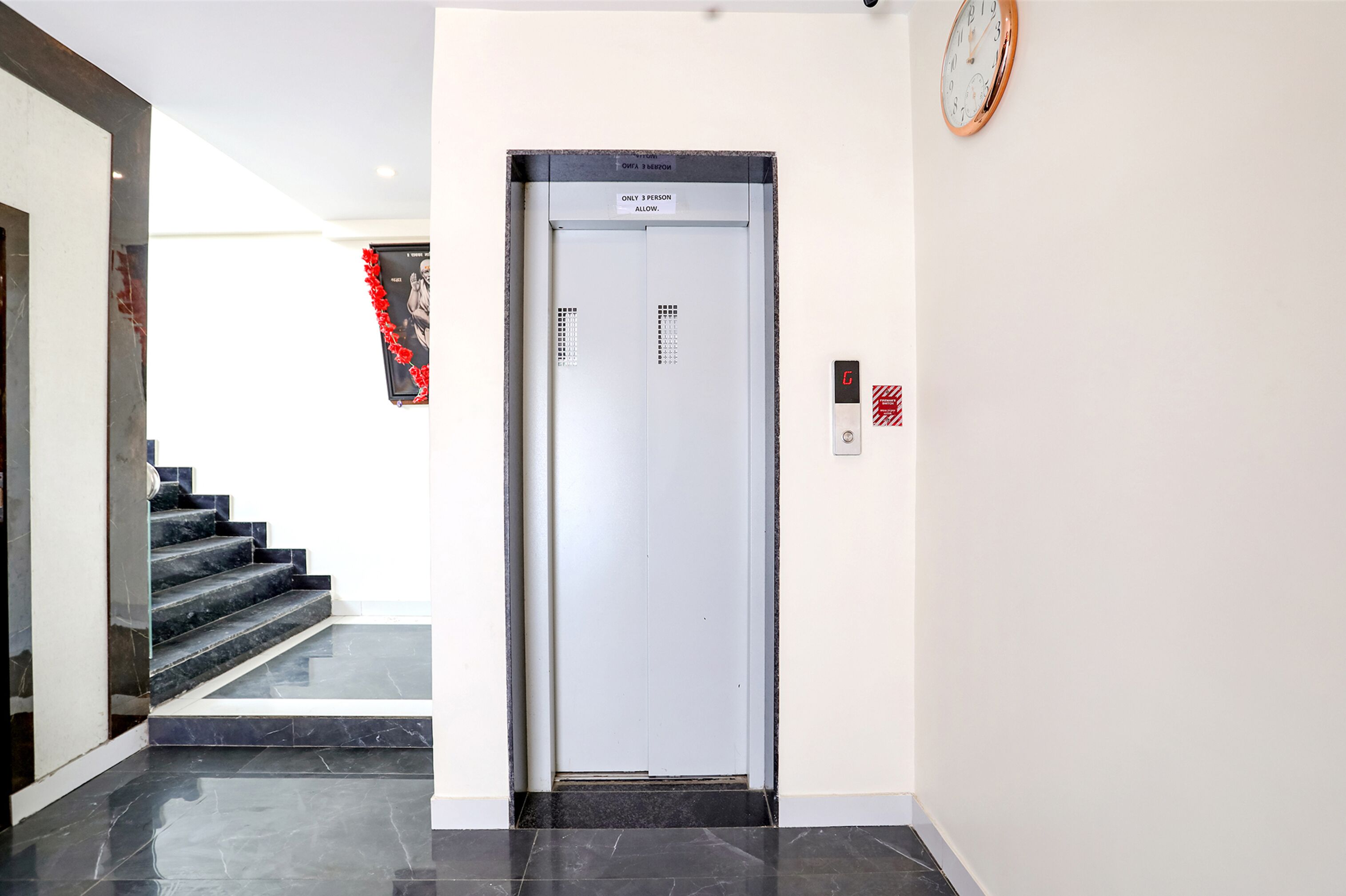 Un ascenseur sur lequel est affiché un panneau indiquant : « Maximum 3 personnes. »