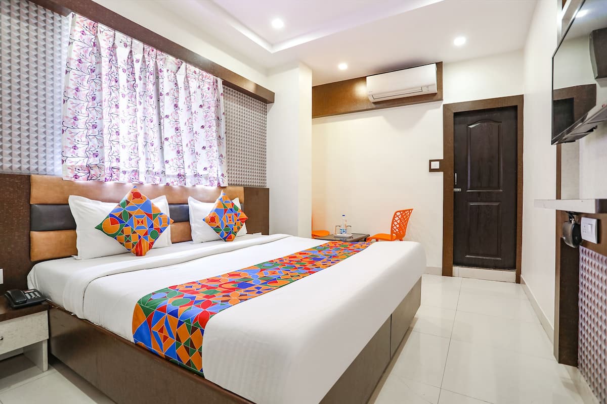 Une chambre d’hôtel avec un grand lit, une table de chevet avec un téléphone, une chaise et une porte.