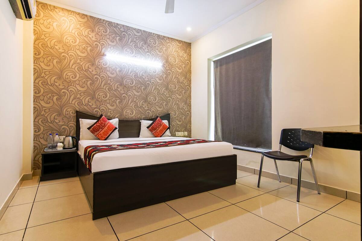 A hotel room with a large bed, a desk, and a chair.