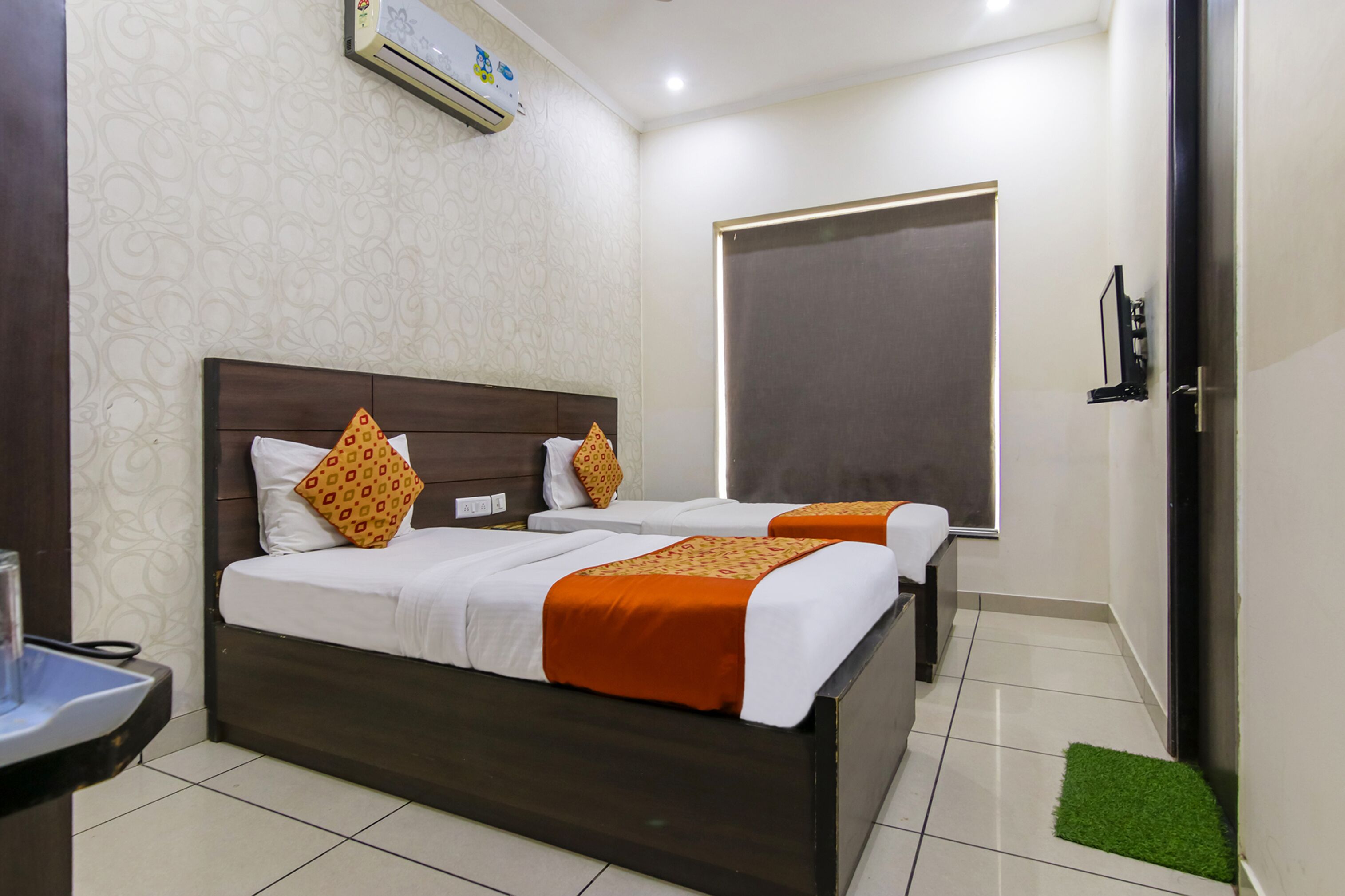 A hotel room with two beds, a bathroom, and a window.