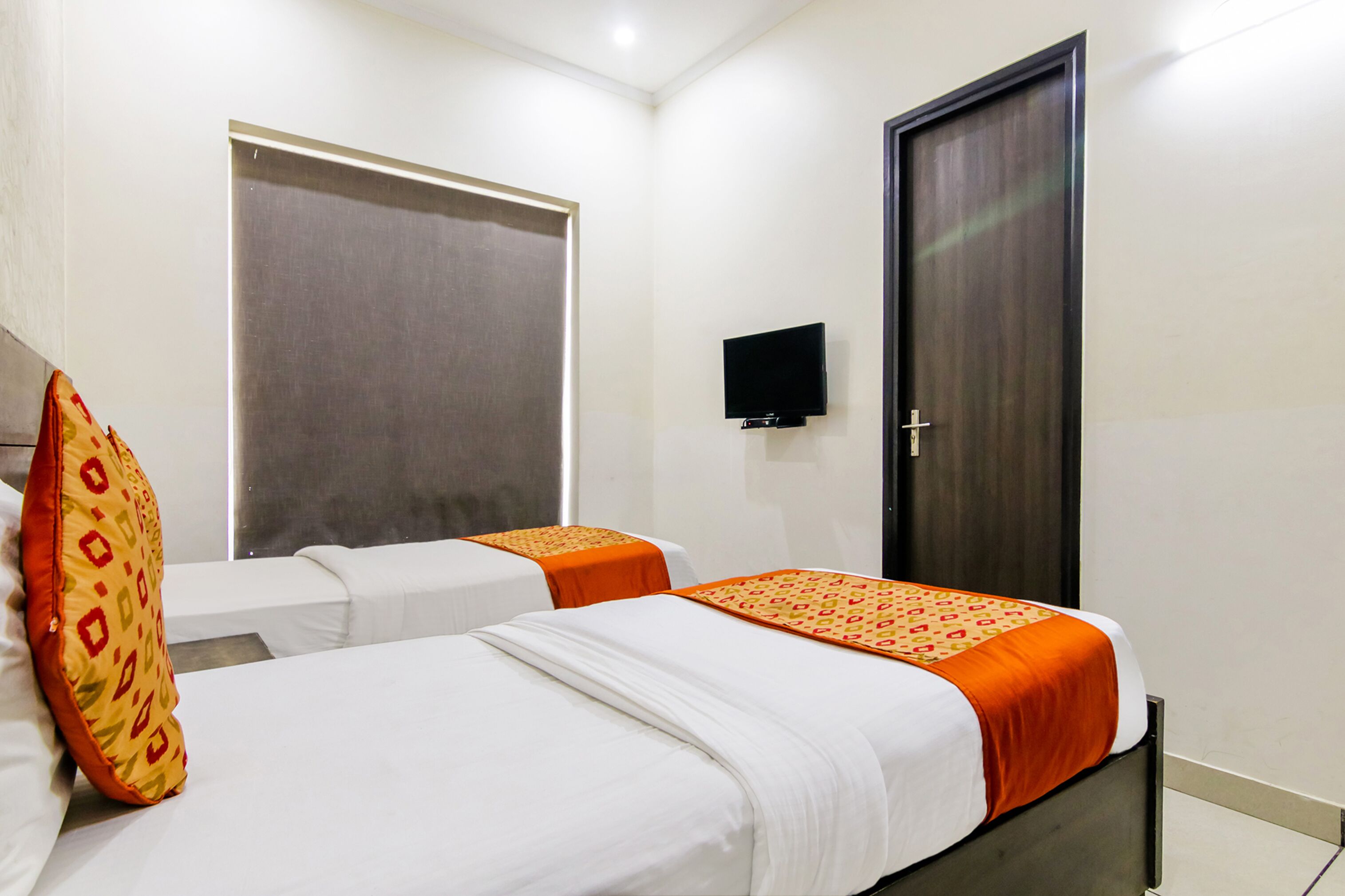 A hotel room with two beds, a television, and a door.