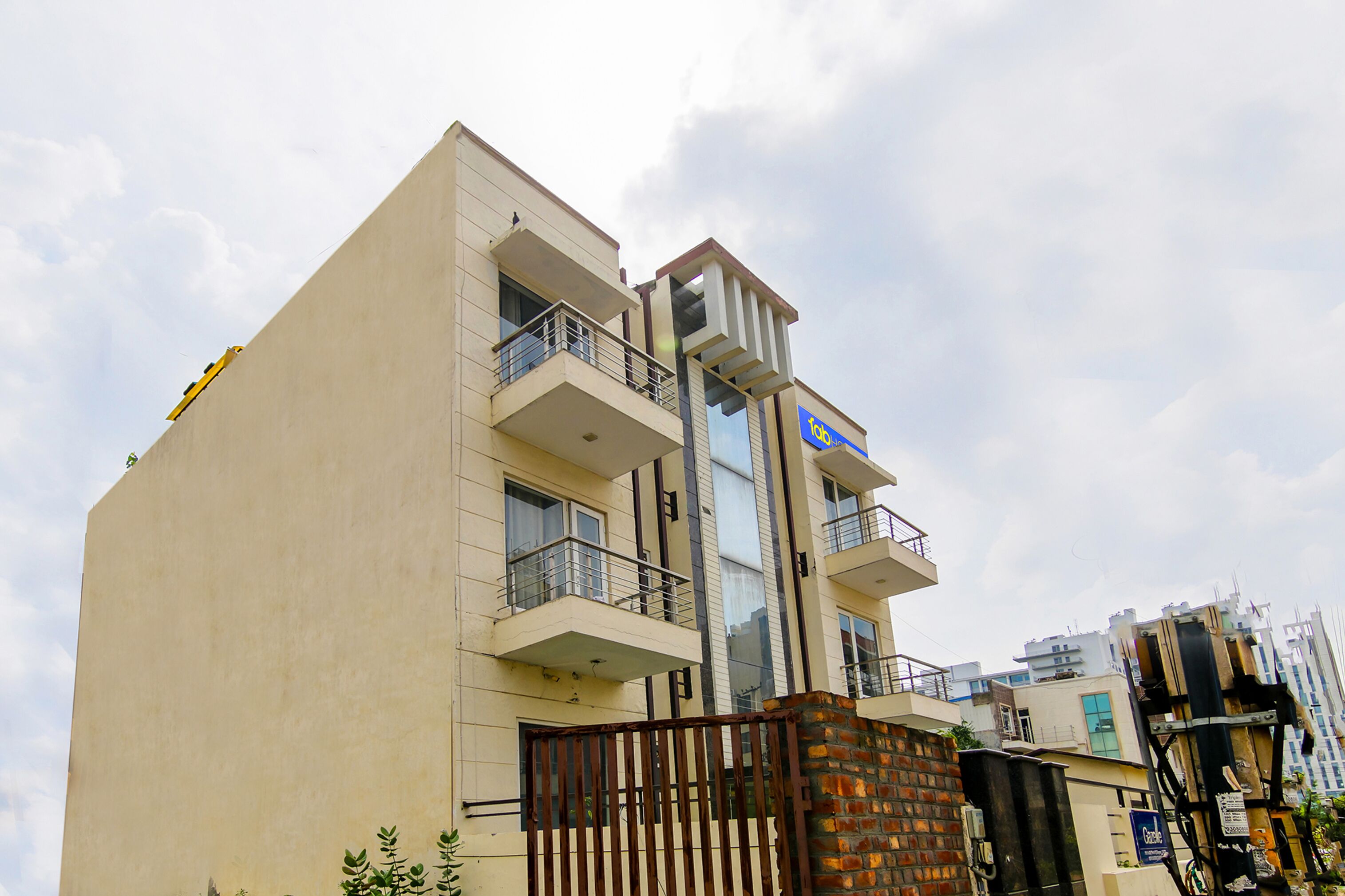 A multi-story building with balconies, a gated entrance, and a visible sign.