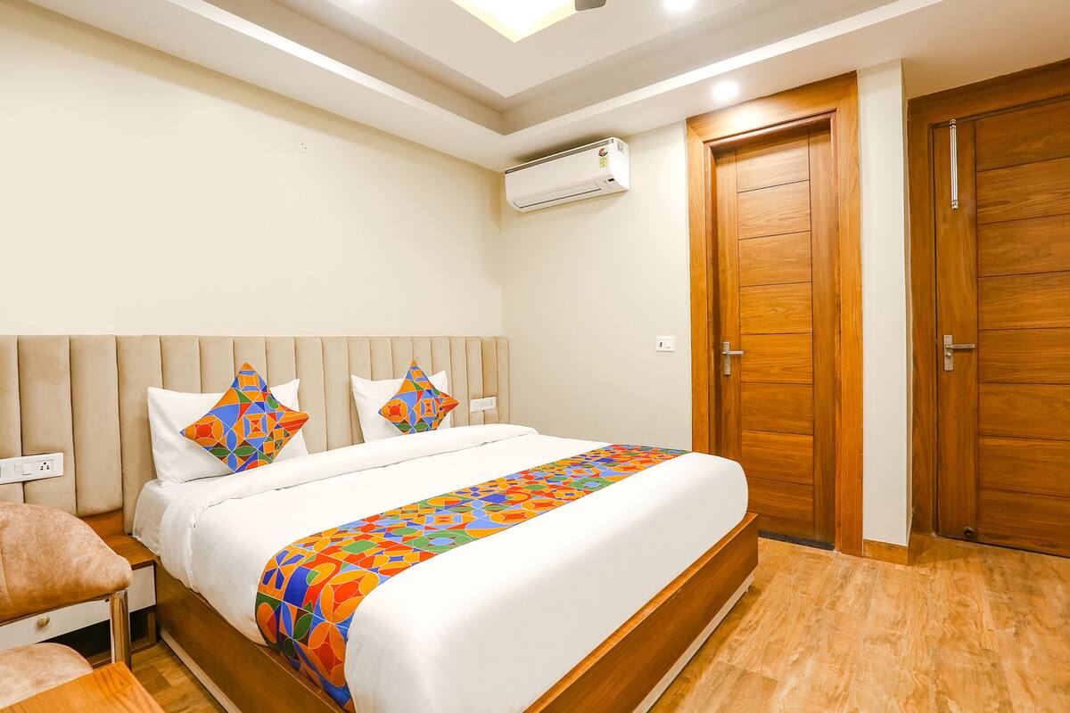 Habitación de hotel ordenada con una cama grande, armario de madera y un equipo de aire acondicionado en la pared.