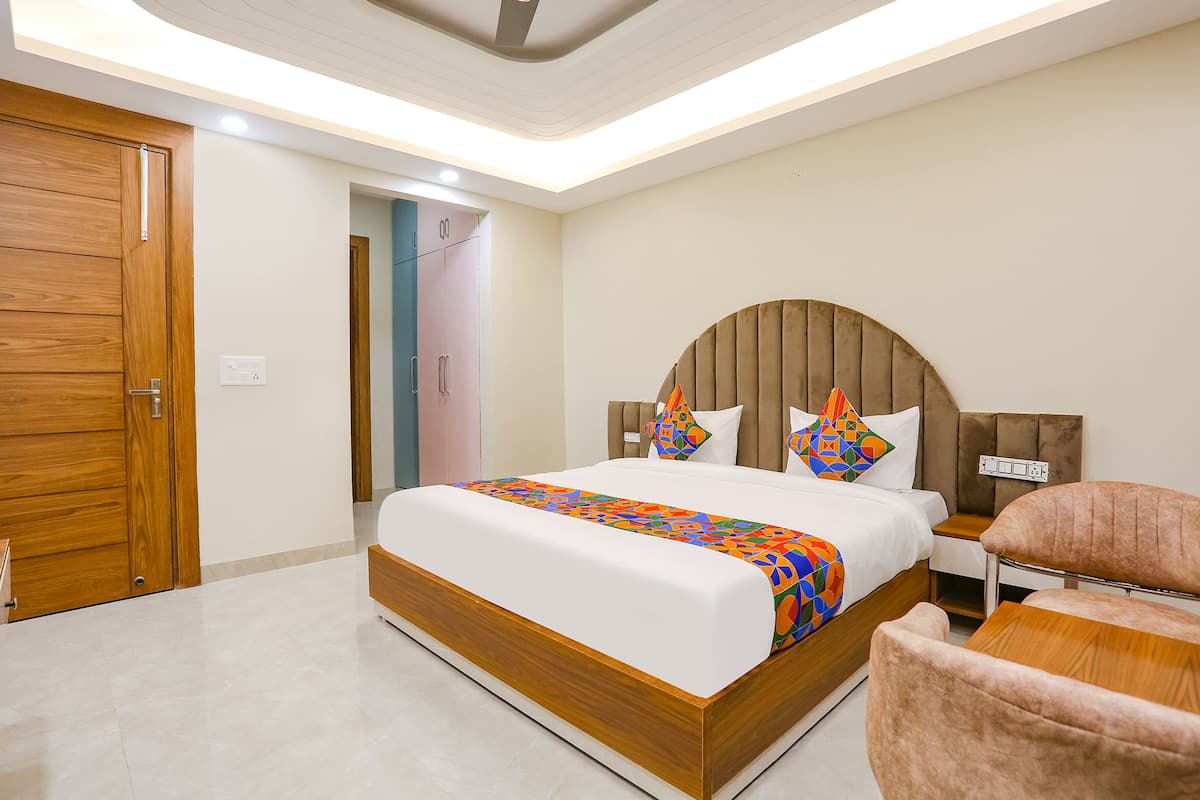 A modern hotel room with a large bed, a wooden door, and a small bedside table.