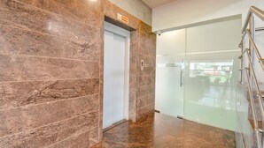 Een modern interieur met een marmeren muur, een glazen deur en een metalen leuning.