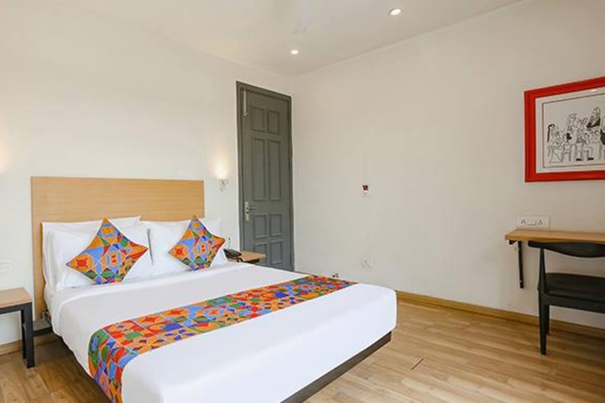 A neatly made bed with colorful pillows, a bedside table, and a framed picture on the wall.