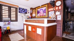 A reception desk with a wooden finish, a clock, and framed pictures on the wall. - FabHotel MM Residency (Chennai)