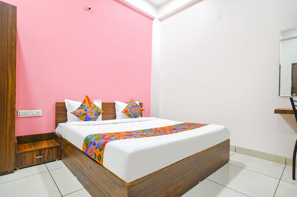 Un dormitorio con cama, cabecero de madera y pared rosa.
