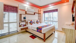 A modern bedroom with a bed, bedside tables, a wardrobe, and a window with a view. - Fabhotel The Lily (Kolkata)