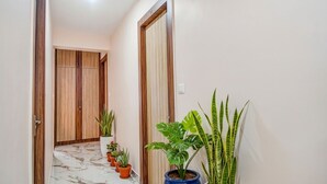 A hallway with a marble floor, wooden wardrobe, and potted plants. - Fabhotel The Lily (Kolkata)