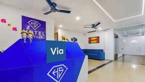 A hotel reception desk with a blue and white color scheme, multiple ceiling fans, a blue sofa, and a painting on the wall. - Fabexpress Solitaire (Surat)