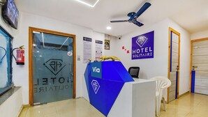 A hotel reception desk with a blue and white color scheme, a ceiling fan, and a fire extinguisher. - Fabexpress Solitaire (Surat)