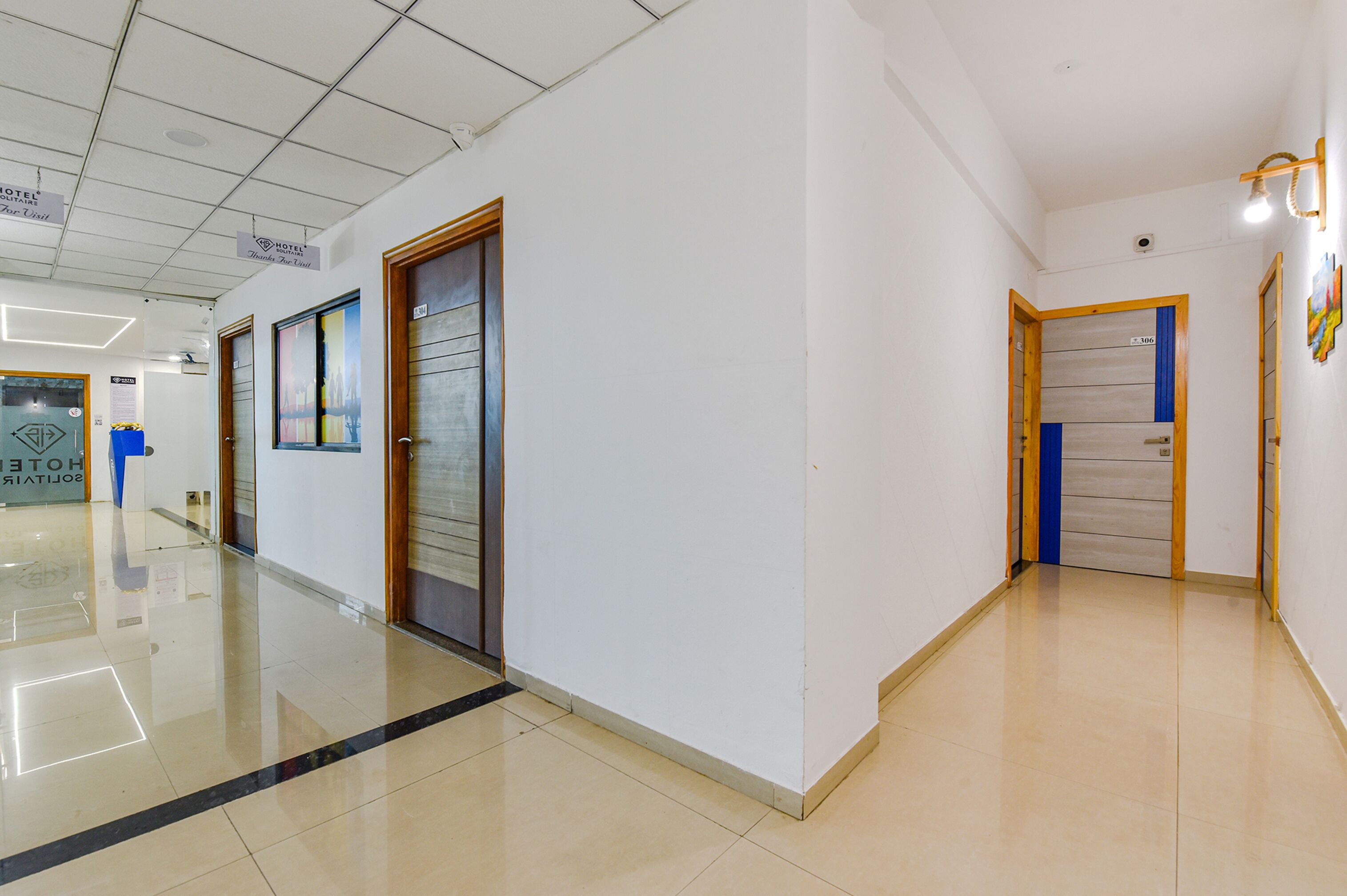Un couloir d’hôtel avec des portes, un espace de réception et un panneau indiquant qu’il s’agit d’un hôtel.