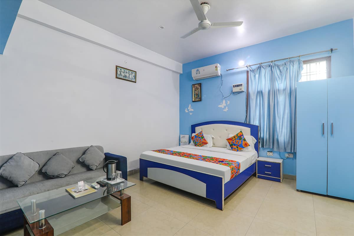 Un dormitorio con cama, sofá, mesa de centro de vidrio, ventilador de techo y armario.