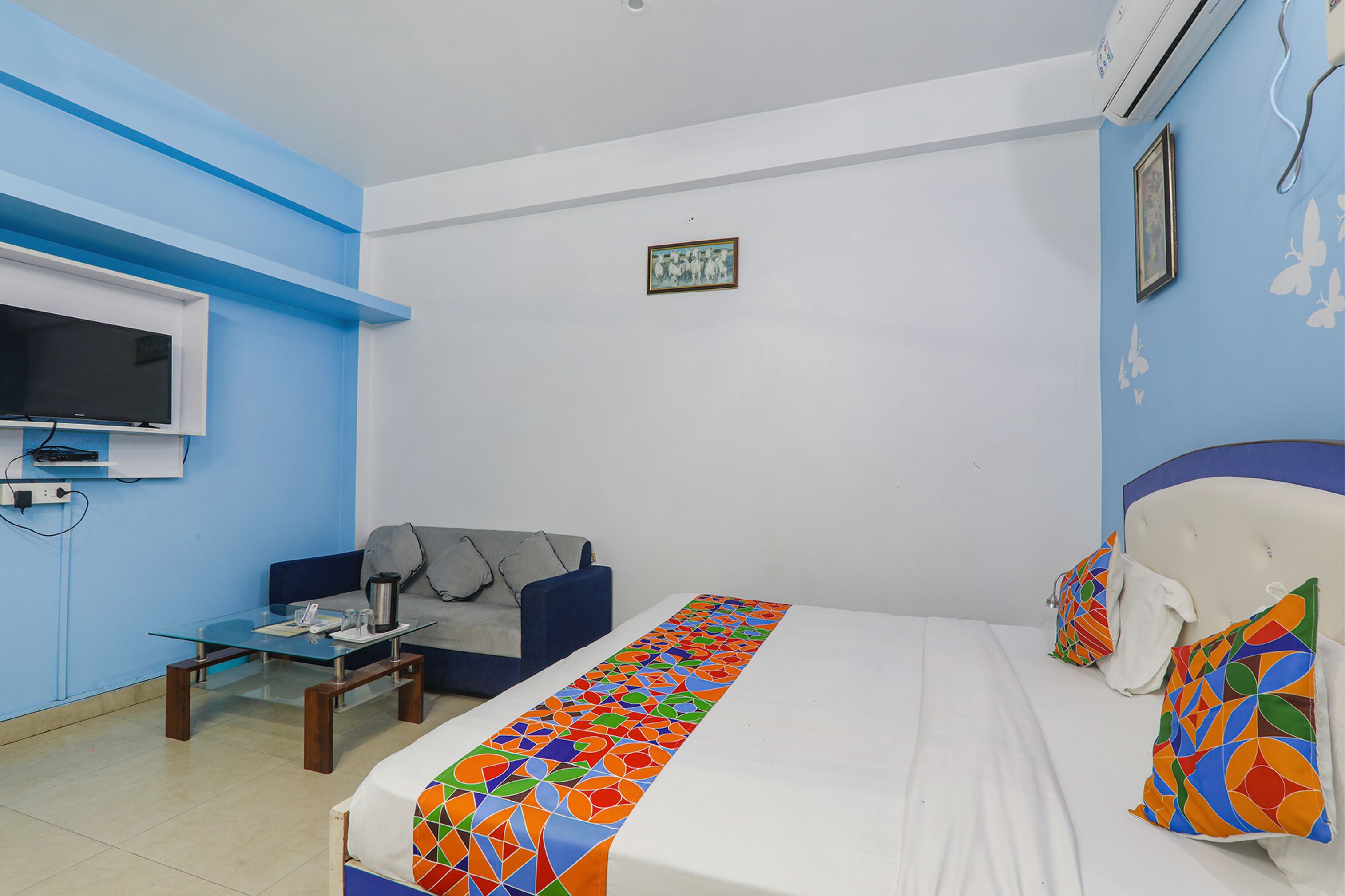 A hotel room with a bed, a sofa, a coffee table, and a TV.