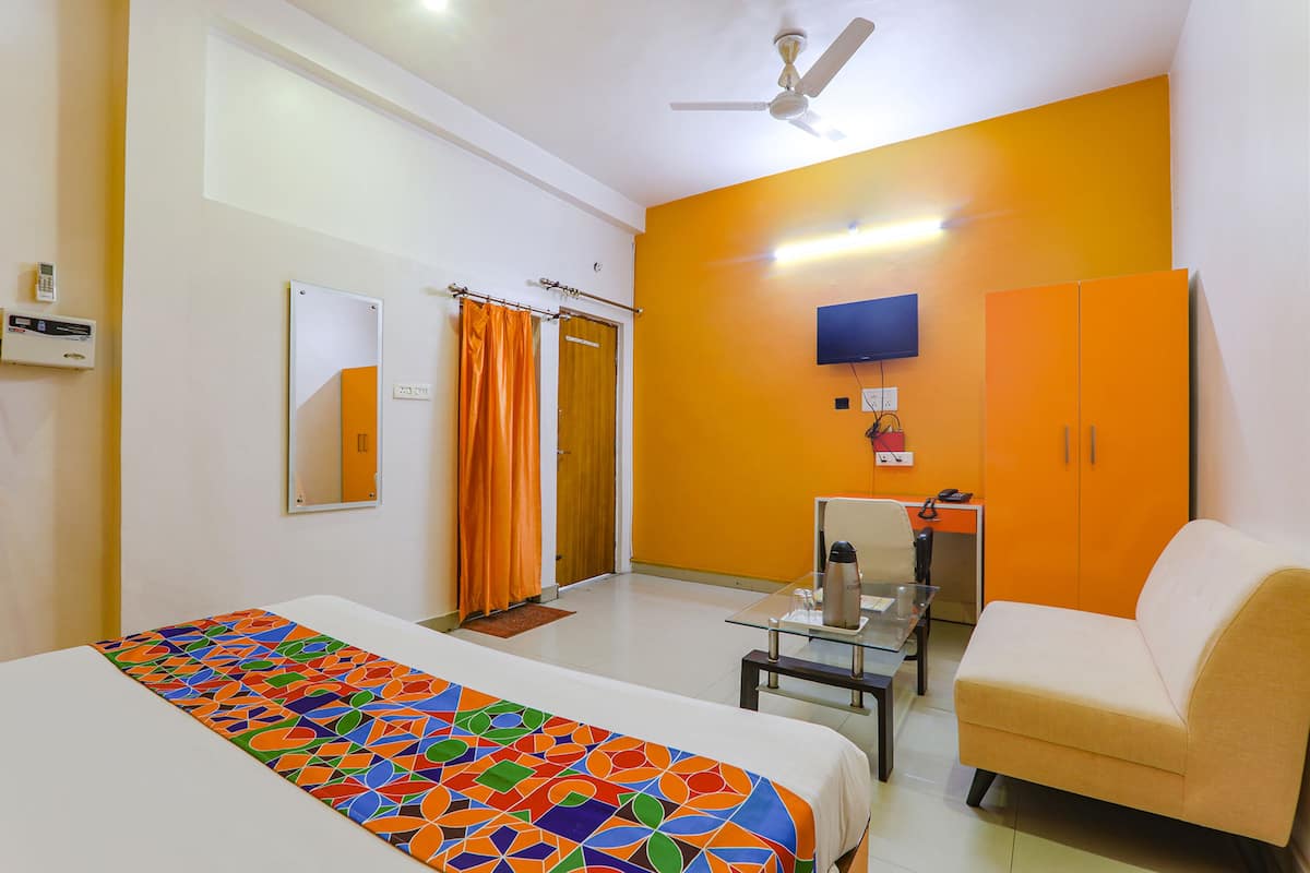 Una habitación de hotel con cama, sofá, televisión y ventilador de techo.