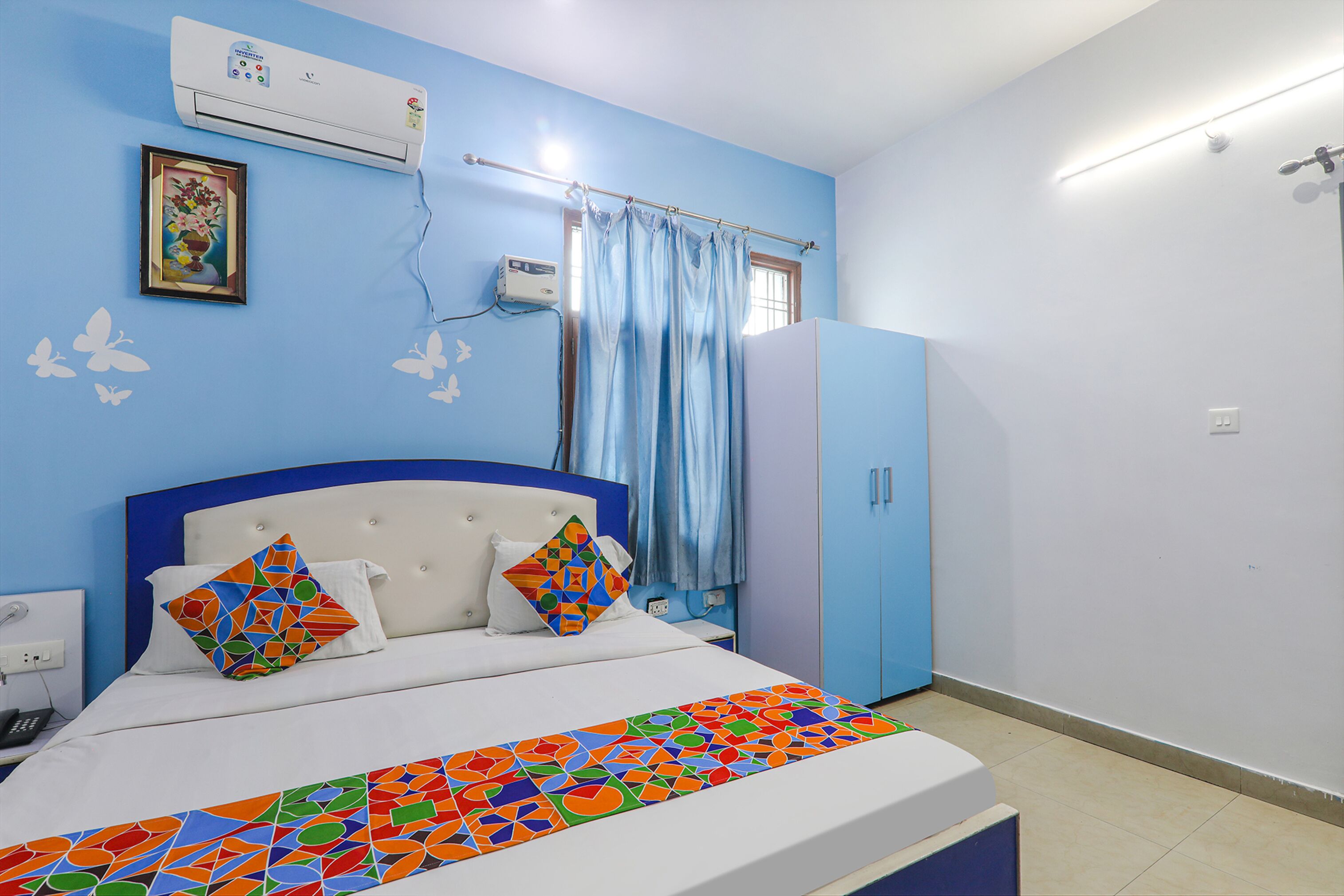Un dormitorio con cama, armario, ventana con cortinas y equipo de aire acondicionado.