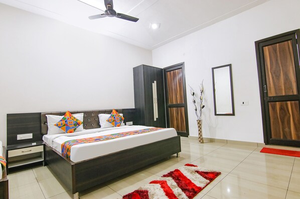 A bedroom with a bed, nightstands, a ceiling fan, and a door.